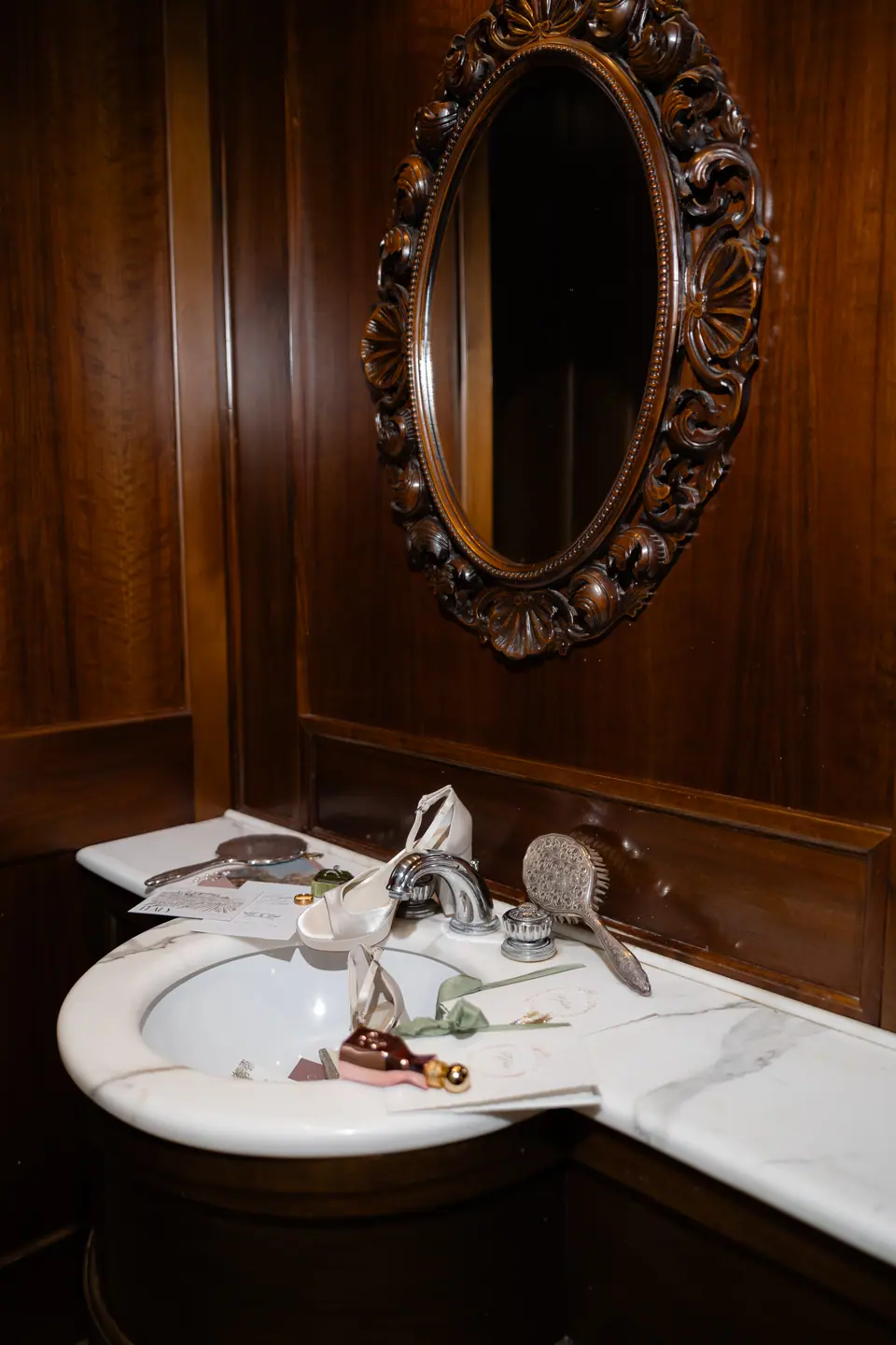 Haley’s bridal details laid out on a marble washbasin in a wood-panelled bathroom
