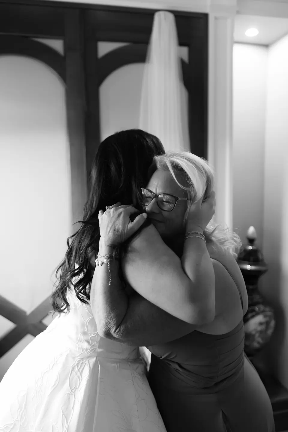Black and white photograph of Haley hugging a woman in glasses, her veil hanging behind them