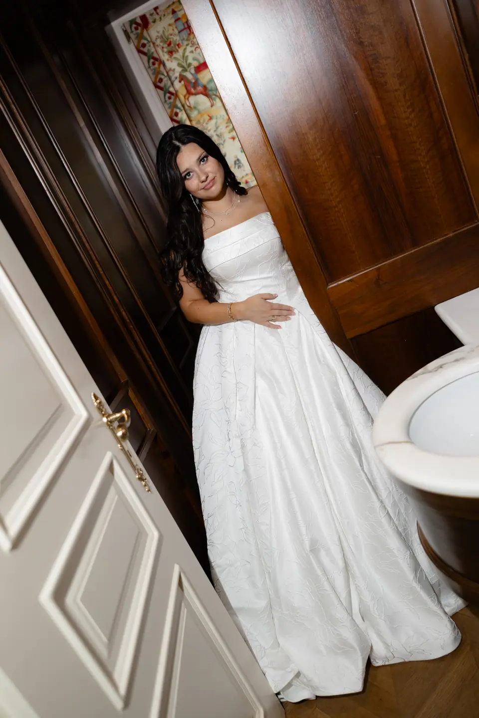 Haley smiling in her strapless gown in a wood-panelled doorway