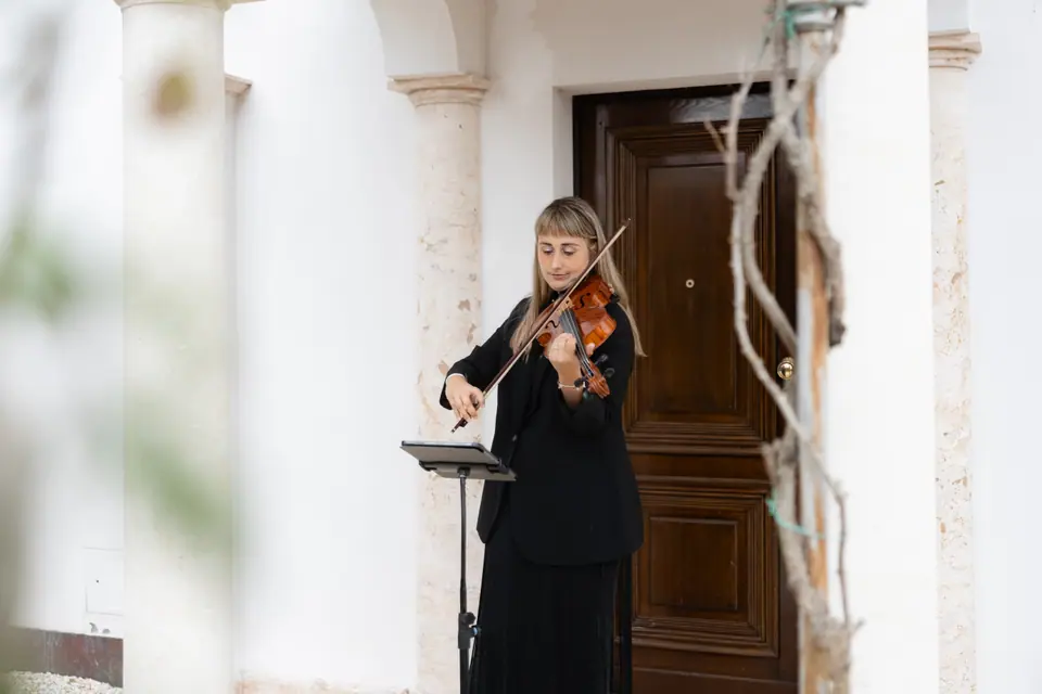 A violinist playing beside the villa’s wooden door
