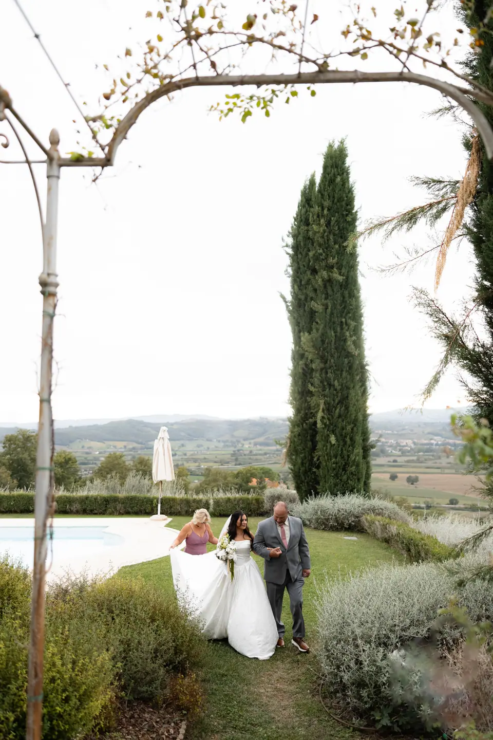 Haley walking up the garden path between a woman in mauve and a man in grey