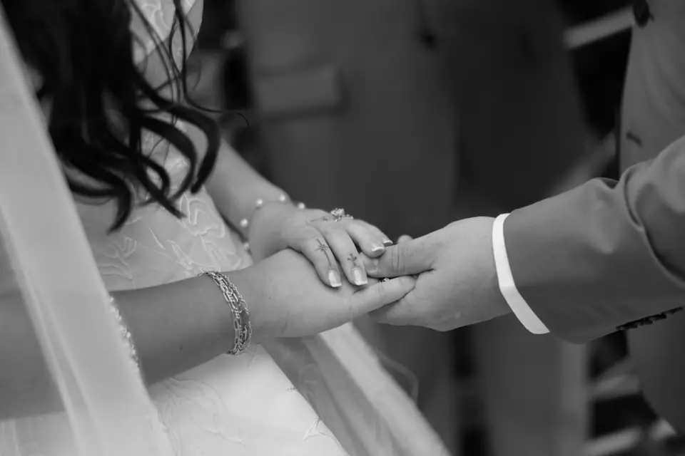 Black and white close-up of Zach sliding the ring onto Haley’s finger