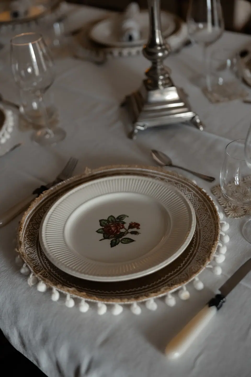 A place setting of rose-patterned china on a beaded charger