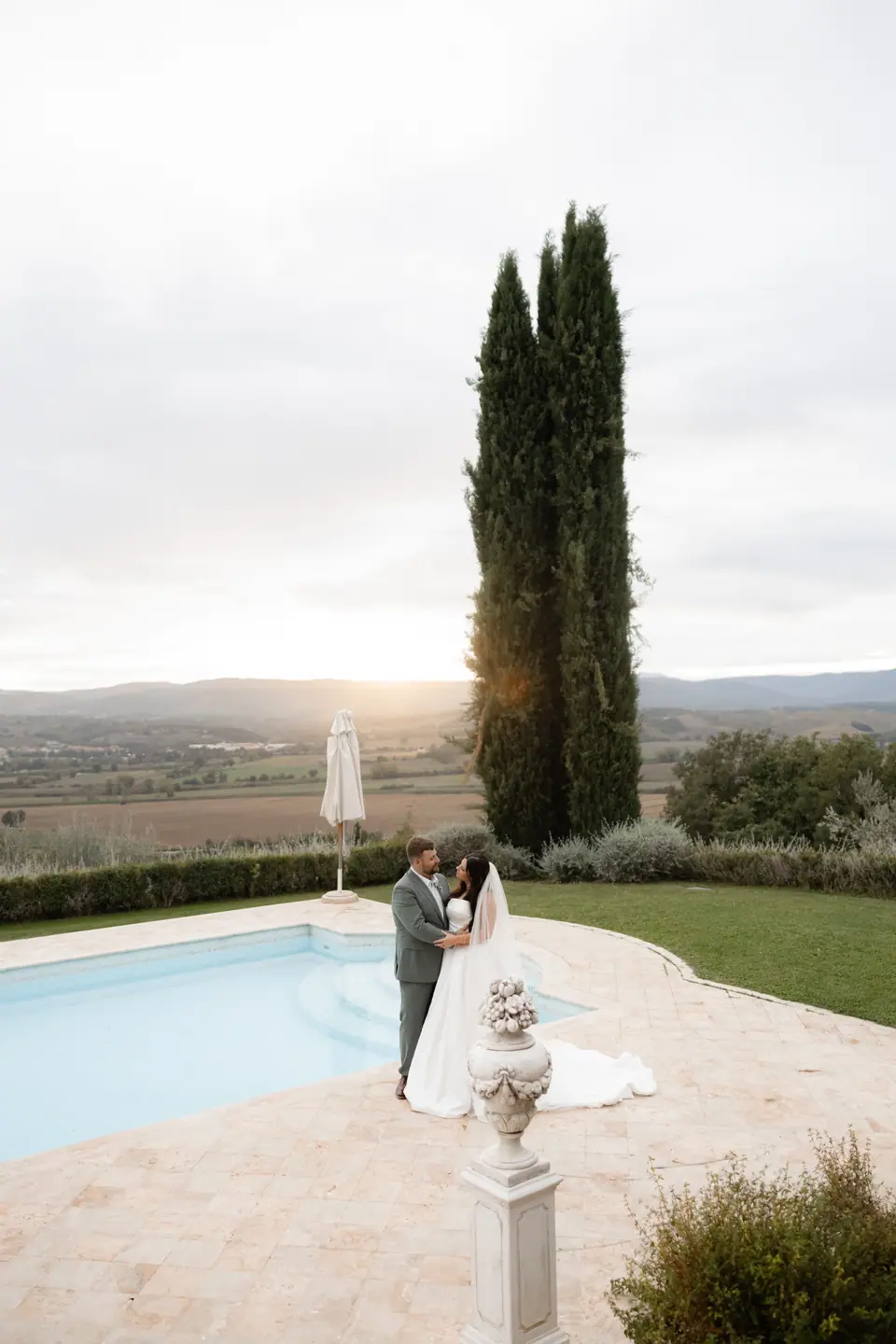 Haley and Zach embracing by the pool as the evening sun breaks through