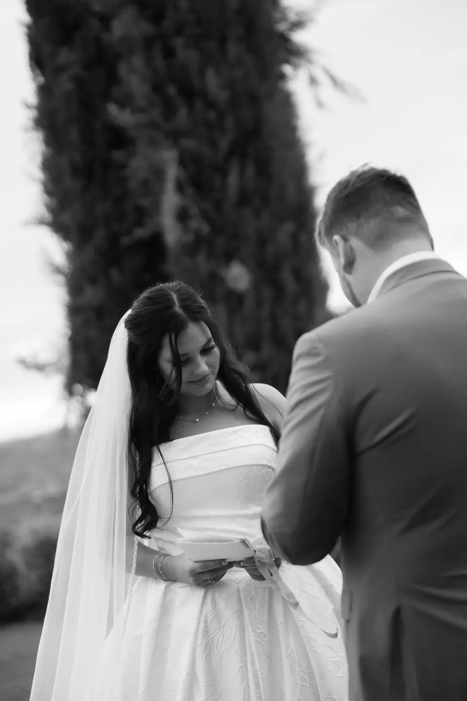 Black and white photograph of Haley and Zach reading letters to each other by the cypress
