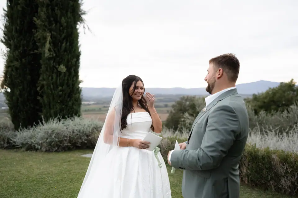 Haley holding a letter and smiling at Zach beside tall cypress trees