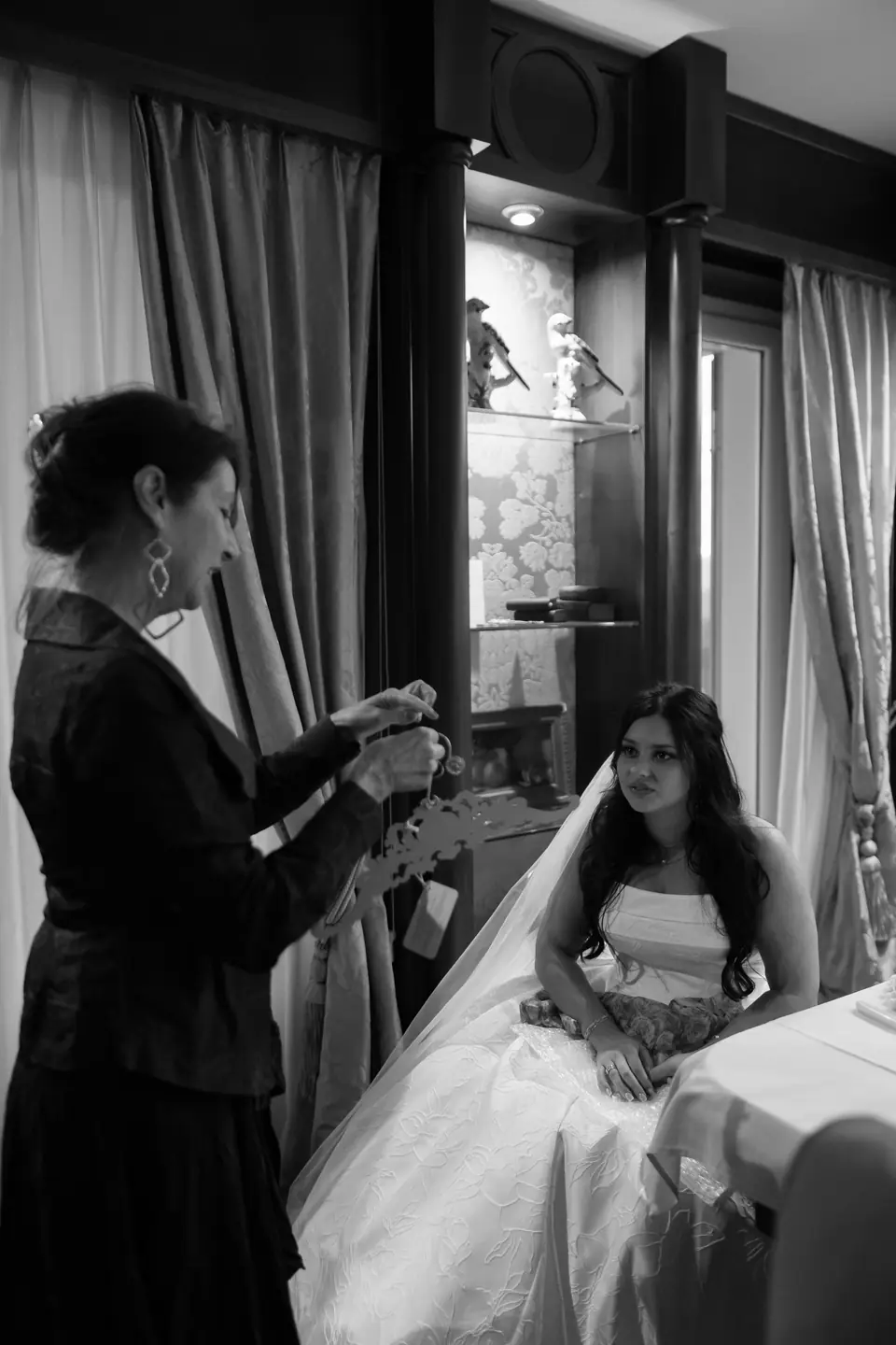 Black and white photograph of a woman in black leaning over Haley as she sits at dinner