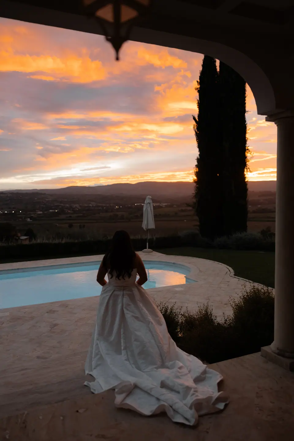 Haley watching the orange sunset over the pool from beneath the villa arch