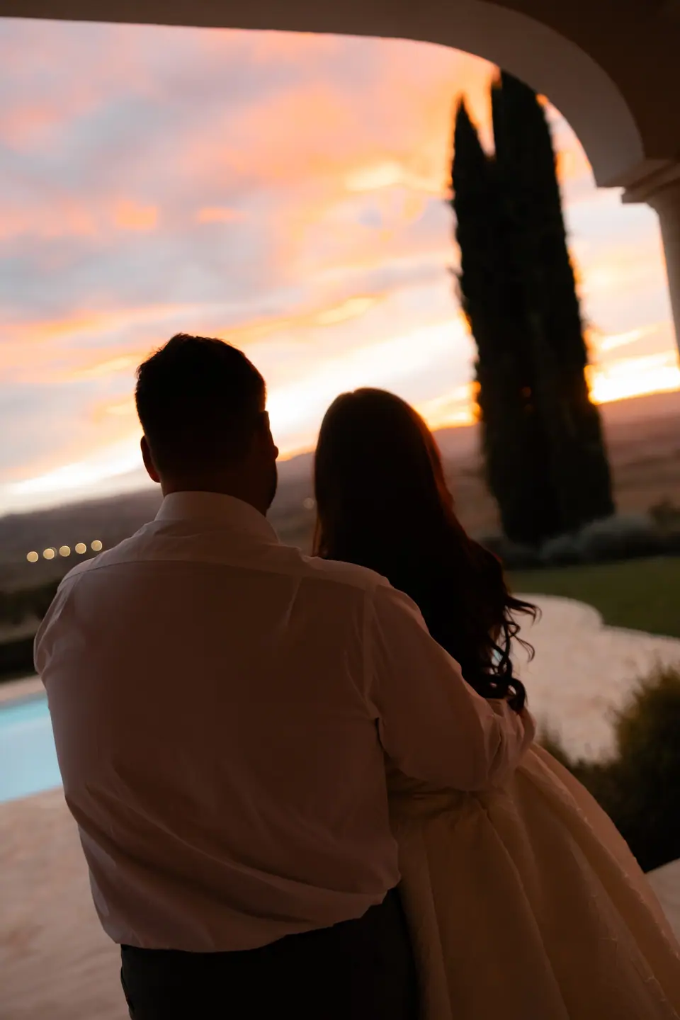 Haley and Zach watching an orange sunset from beneath a villa arch