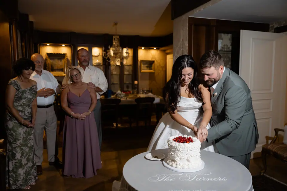 Haley and Zach cutting their cake as their families look on