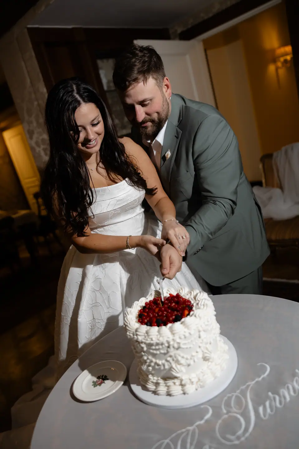 Haley and Zach laughing as they cut the berry-topped cake together