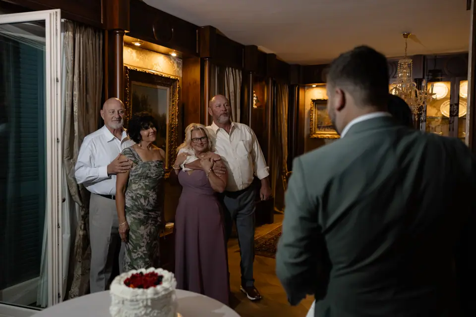 Family members smiling as they watch the cake cutting, Zach in the foreground
