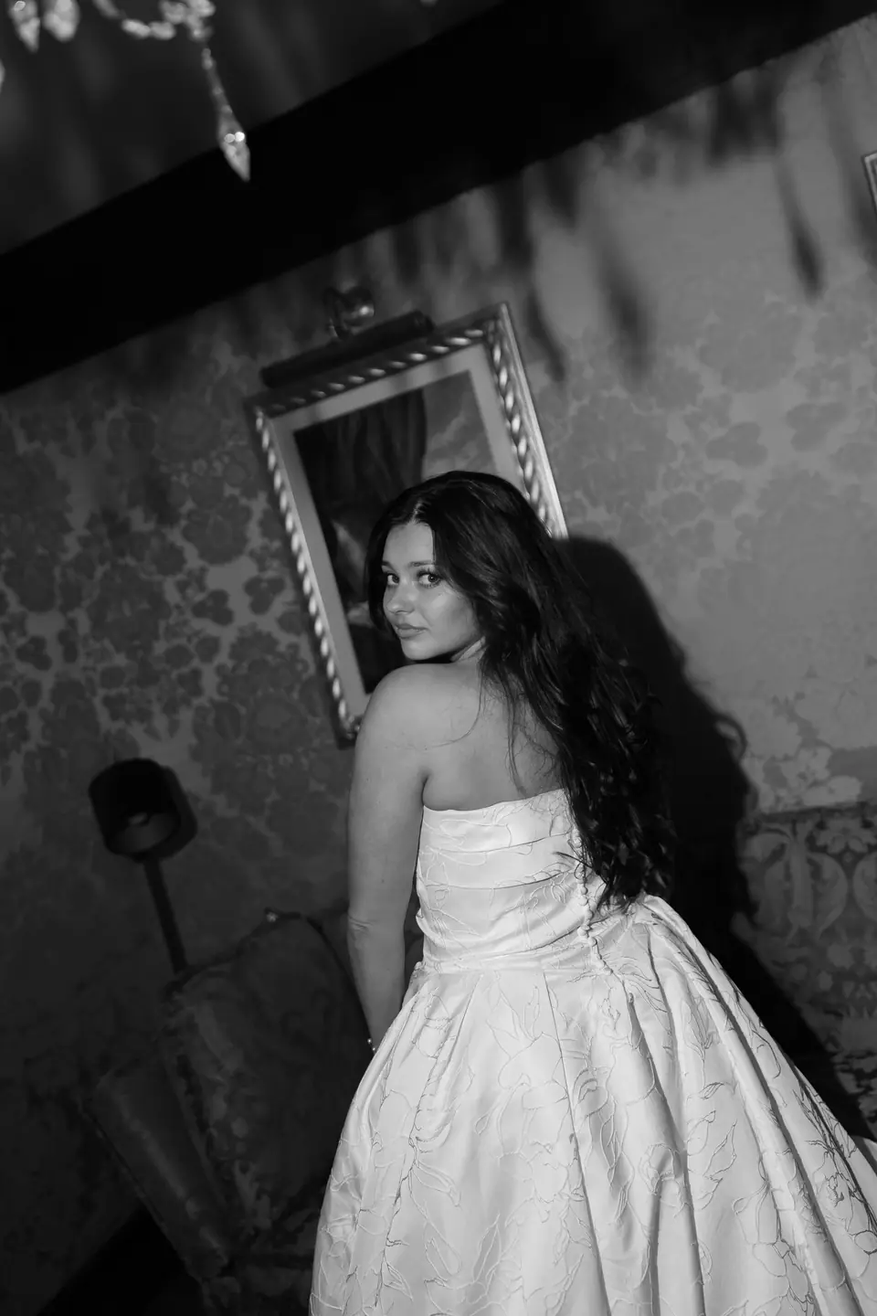 Black and white photograph of Haley glancing over her shoulder beneath a framed painting