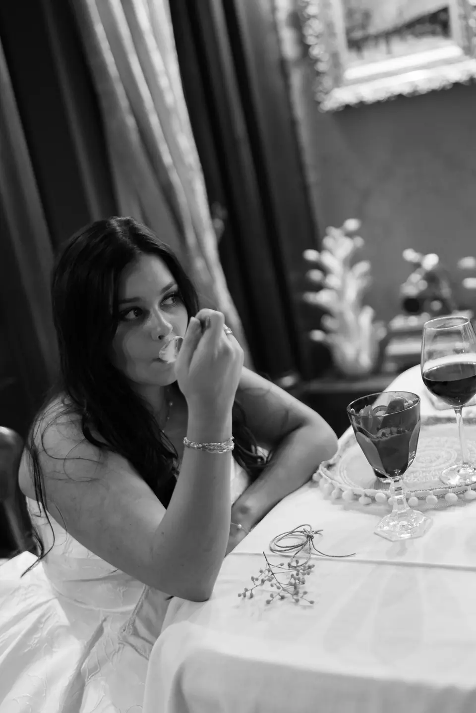 Black and white photograph of Haley at the table, a glass of red wine beside her
