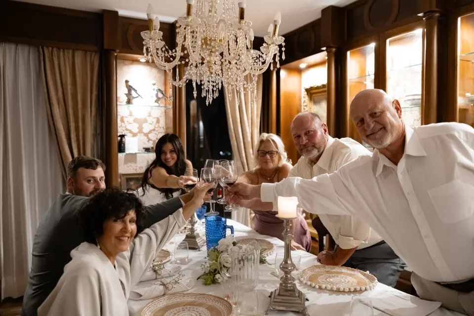 Everyone raising a toast around the dinner table under the crystal chandelier