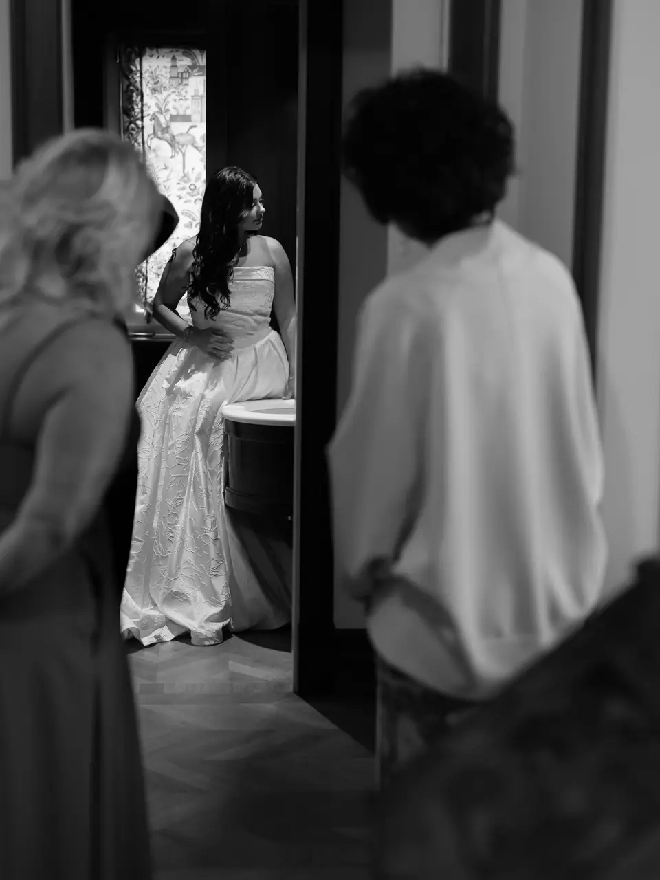 Black and white photograph of Haley seen through a doorway as two women wait