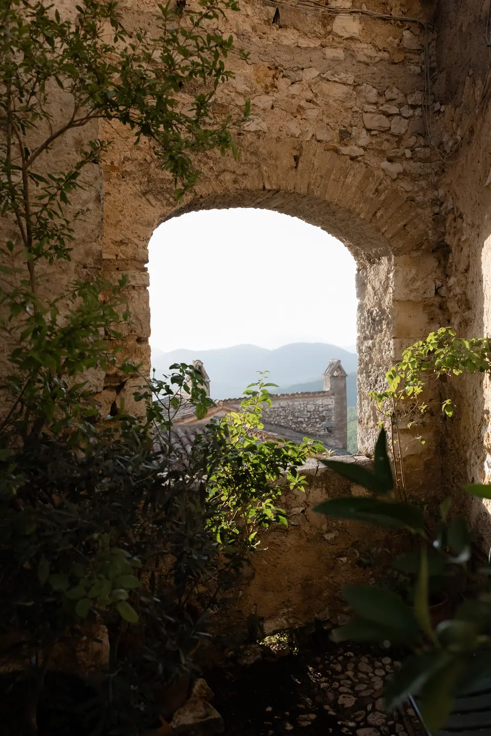 Stone archway in a village garden opening onto distant mountains
