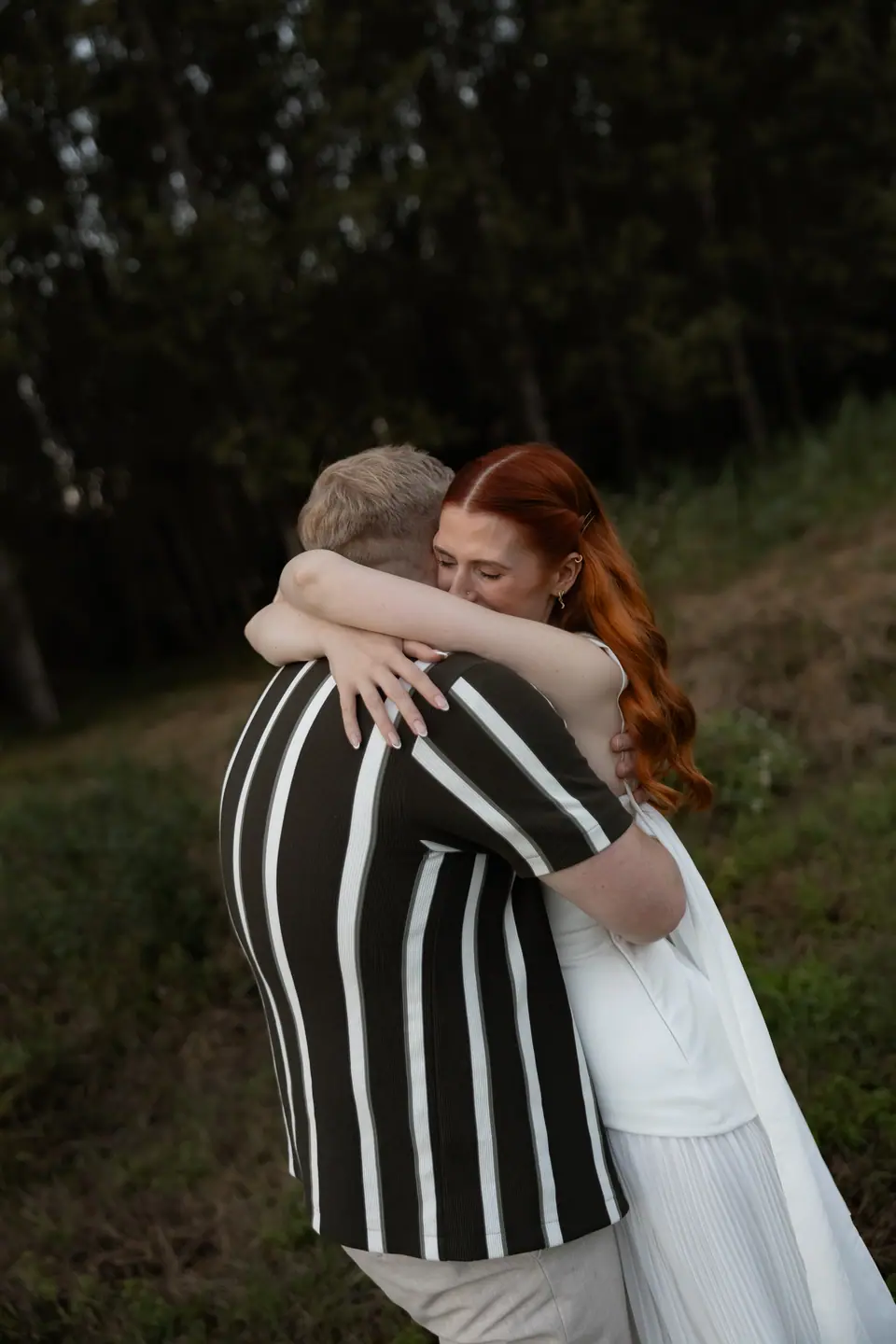 Kate and James hugging in a clearing in the woods