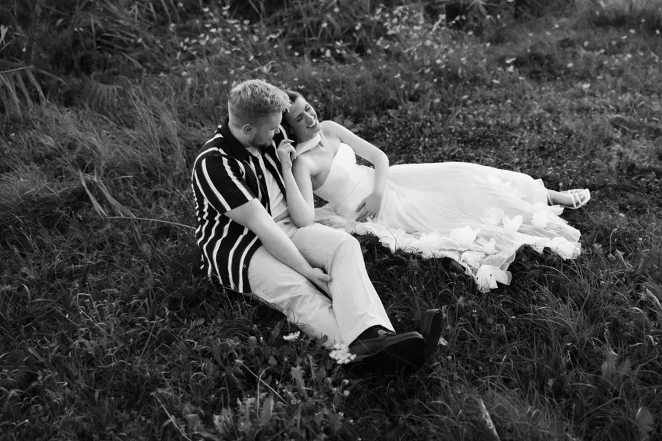 Black and white of Kate and James lying together in the long grass