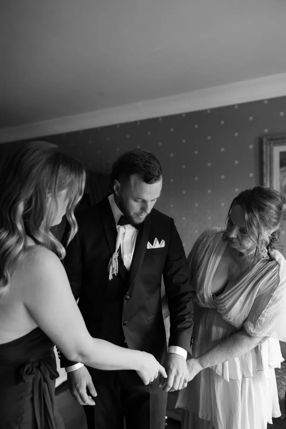 Black and white photograph of two women helping Rory with his cufflinks