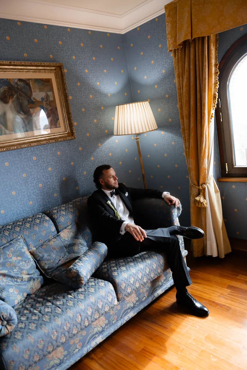 Rory relaxing in his tuxedo on a blue damask sofa before the ceremony
