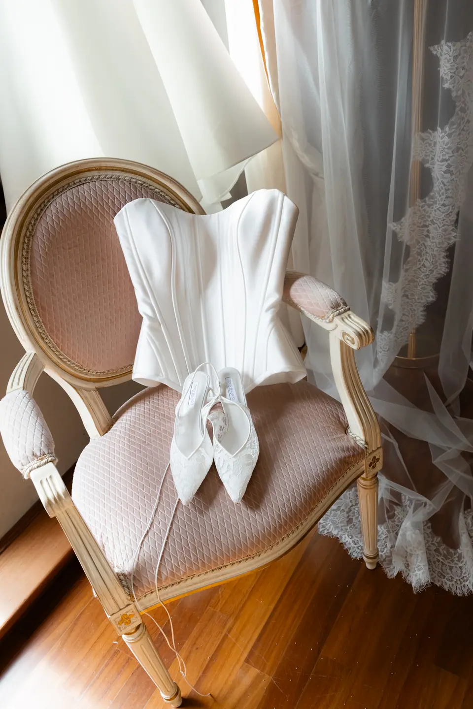 Sivitha’s corset bodice and shoes on a pink velvet chair by the lace curtain