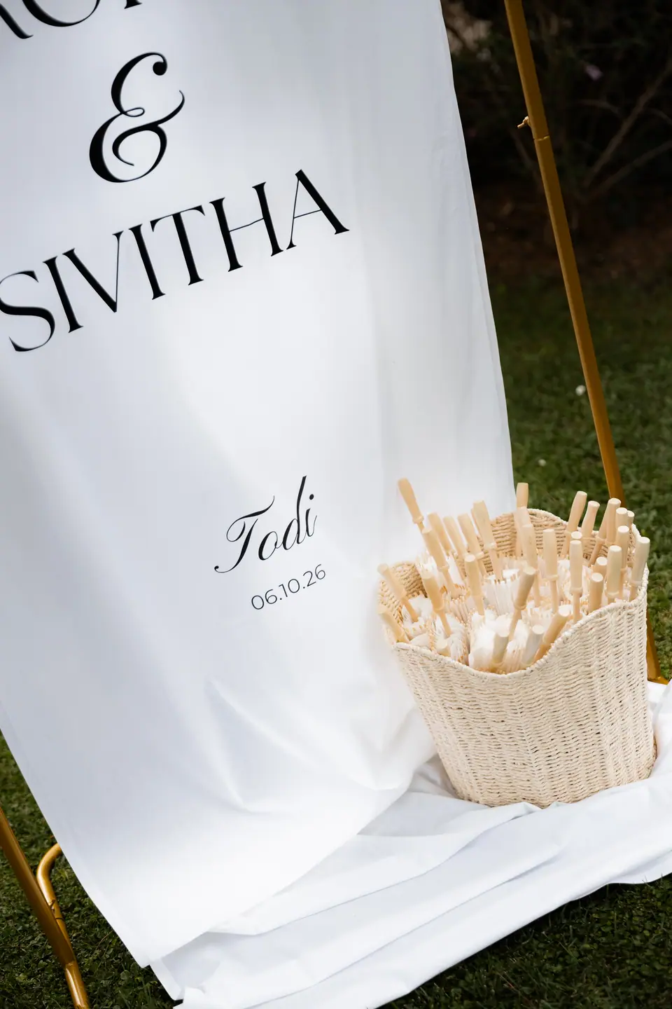 The “Rory & Sivitha, Todi 06.10.26” sign beside a basket of paper fans