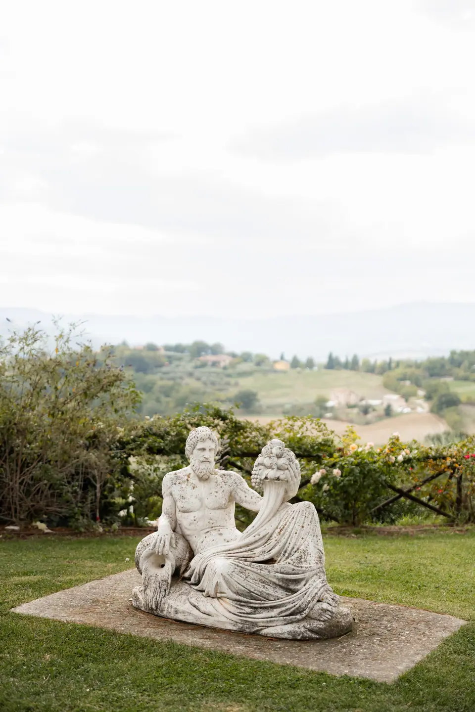 A marble statue of a reclining river god on the lawn above the valley