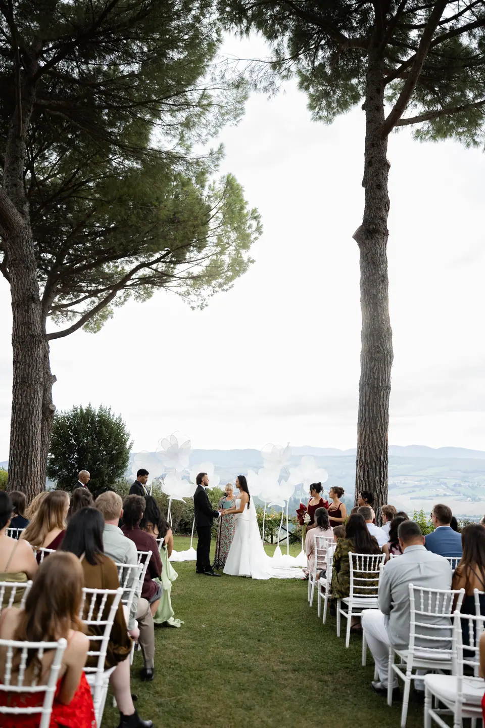 The ceremony seen down the aisle between umbrella pines, the valley beyond