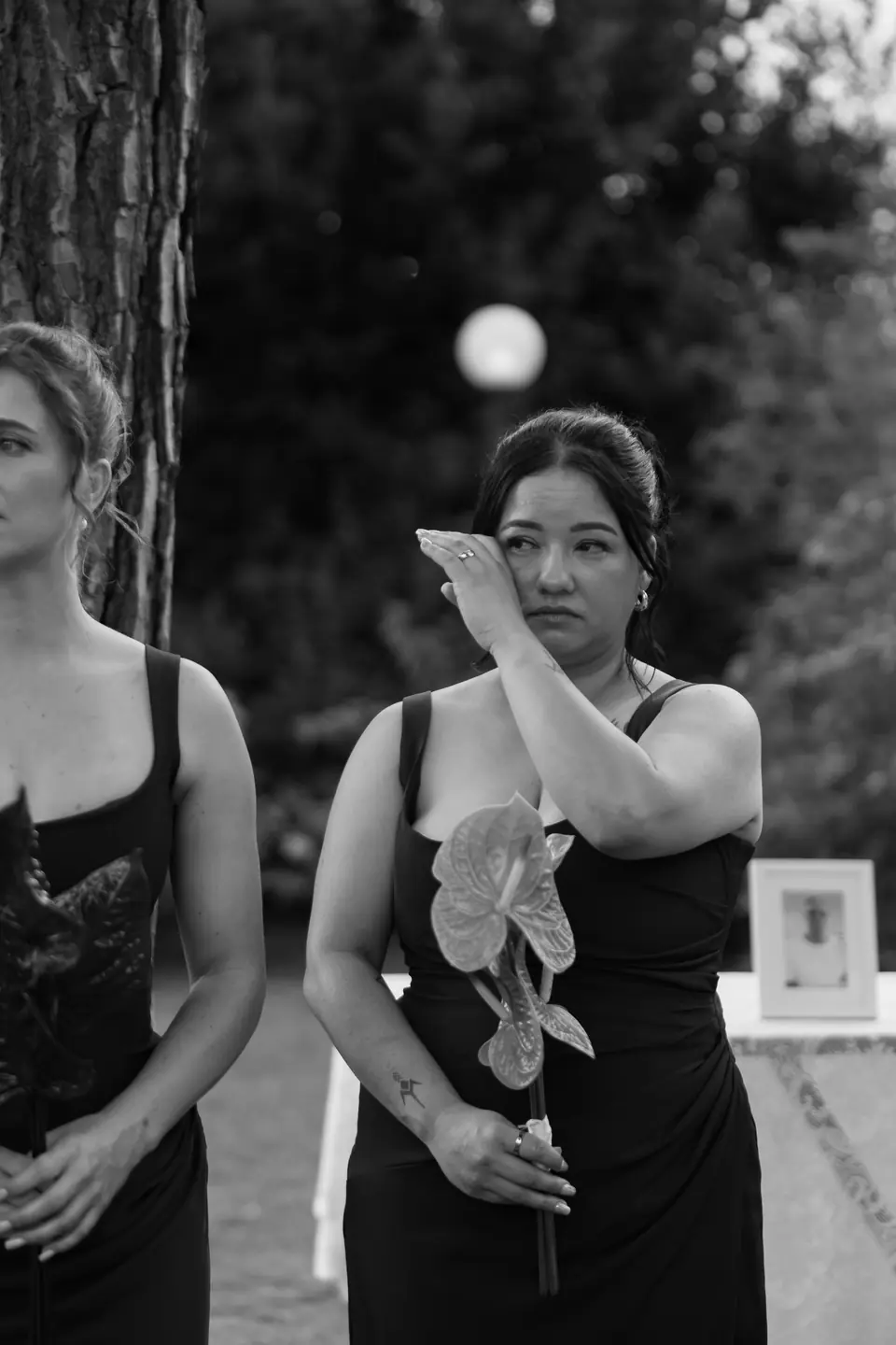 Black and white photograph of a bridesmaid wiping away a tear during the vows