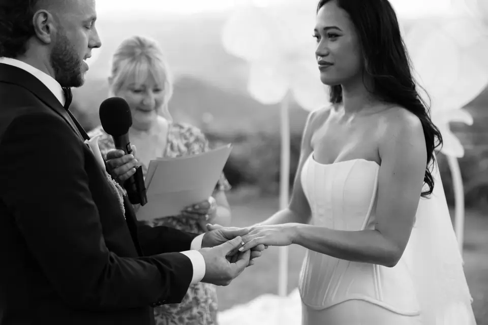 Black and white close-up of the ring exchange beside the celebrant