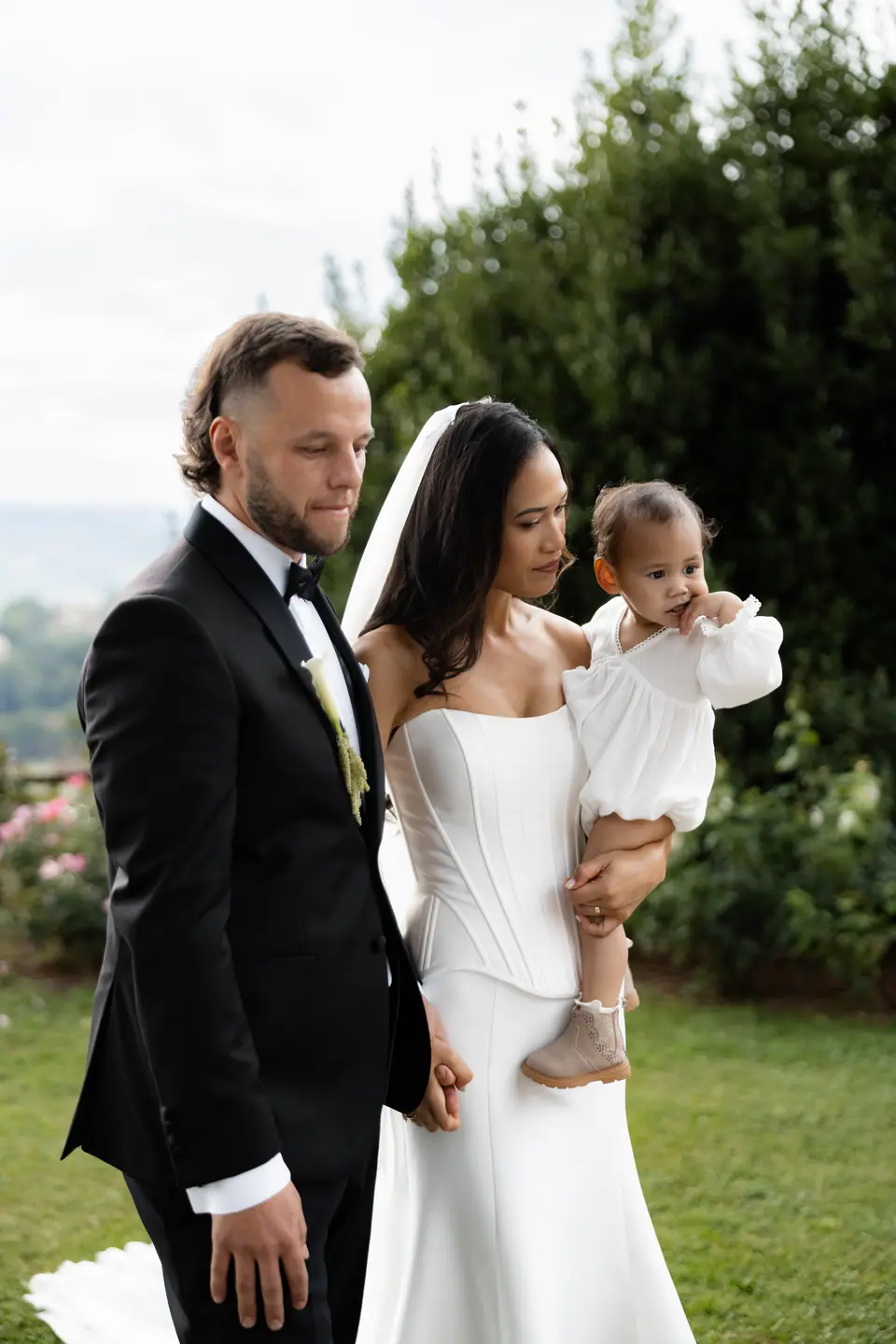 Sivitha holding a toddler in white beside Rory at the ceremony
