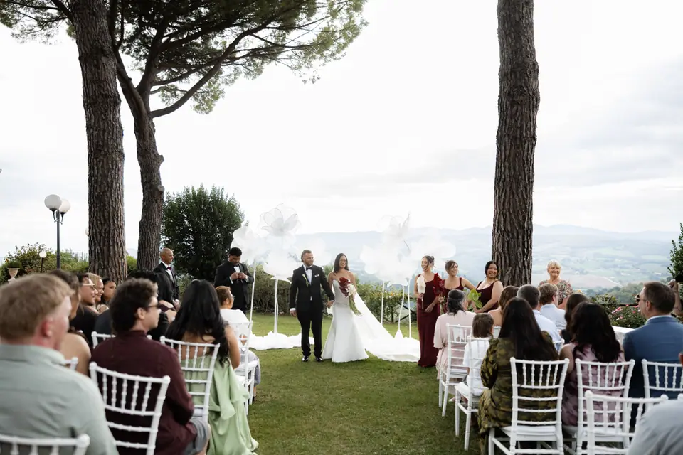 Guests watching the newlyweds from the aisle between the pines