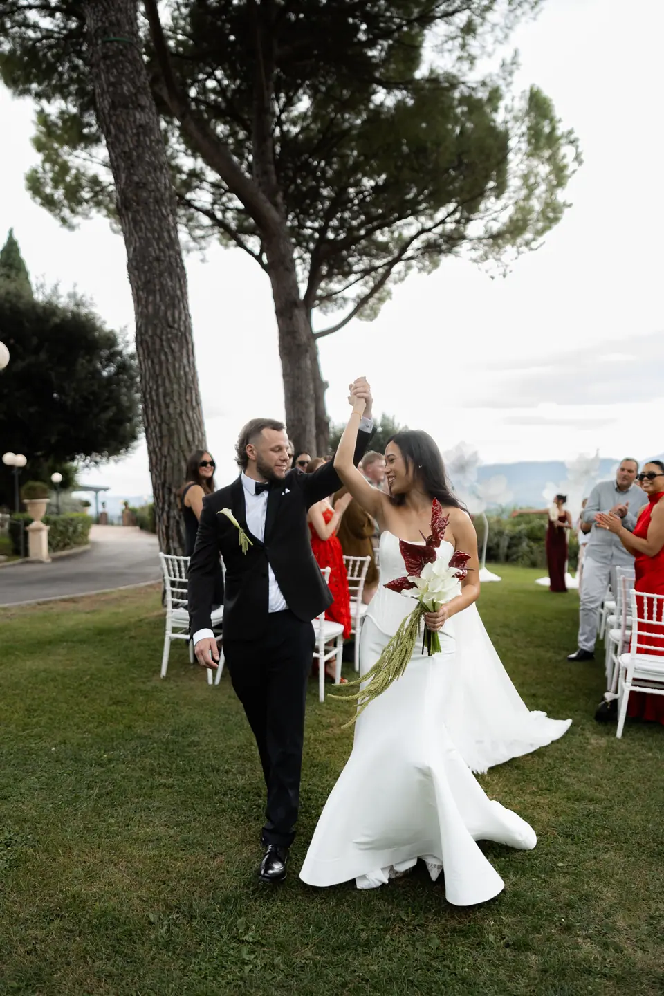 Sivitha and Rory raising their hands in celebration as they walk back down the aisle