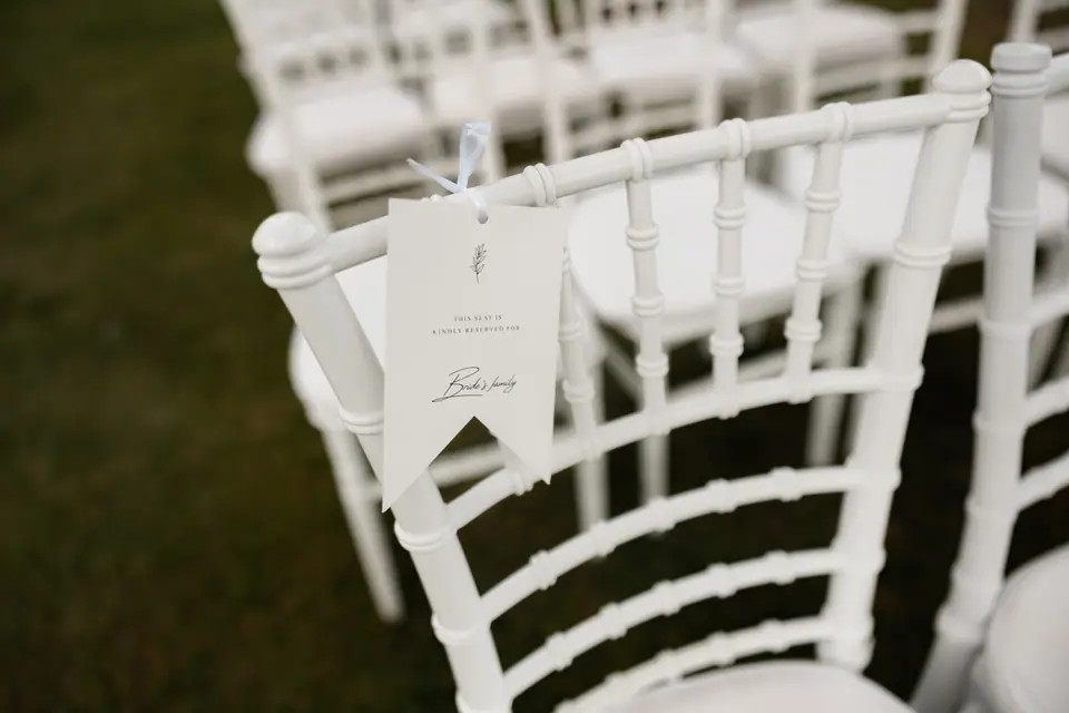 A handwritten card hanging from a white chair in the garden