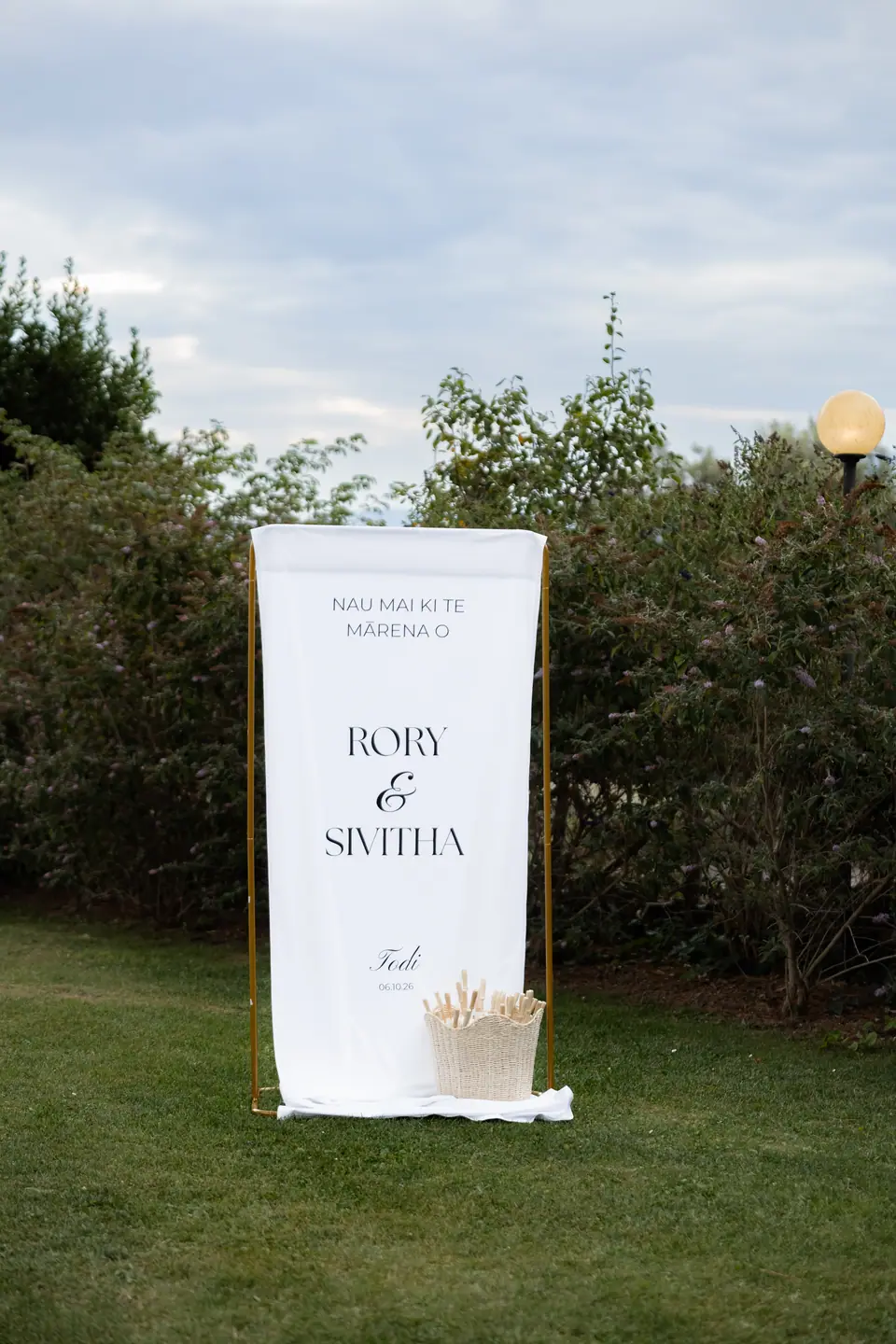 A welcome sign in te reo Māori for Rory and Sivitha standing in the garden