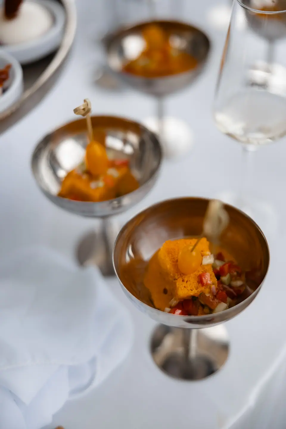 Canapés served in silver coupes on a white table