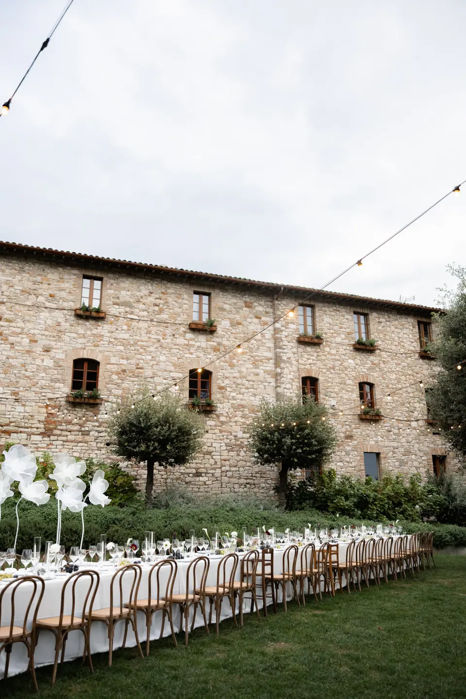 The long dinner table on the lawn beneath the monastery’s stone walls