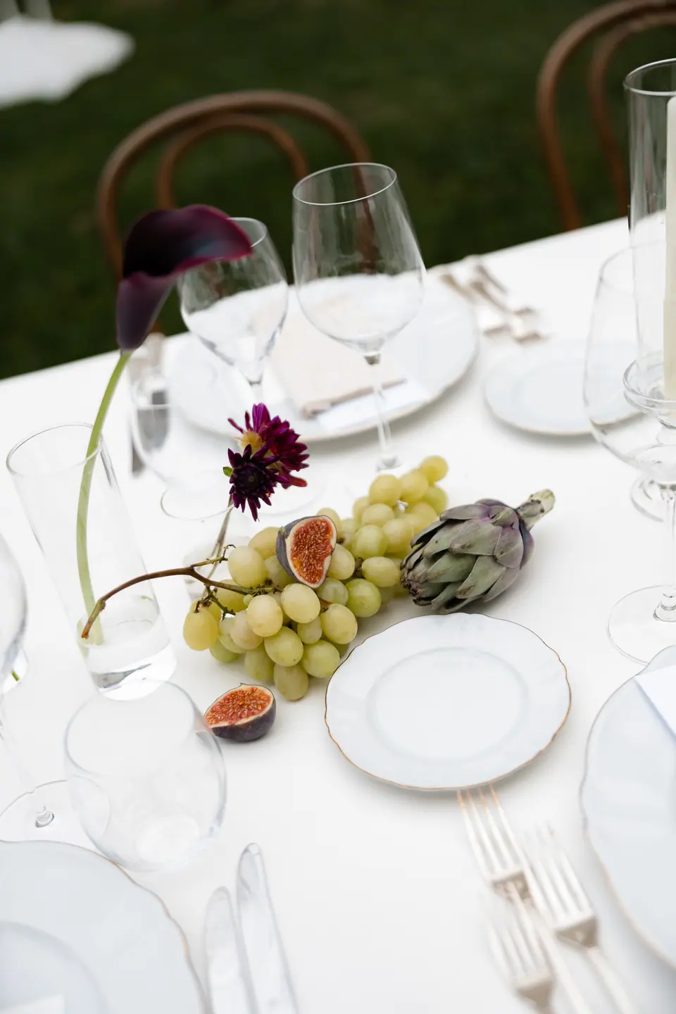 A place setting with figs, grapes and a dark calla lily