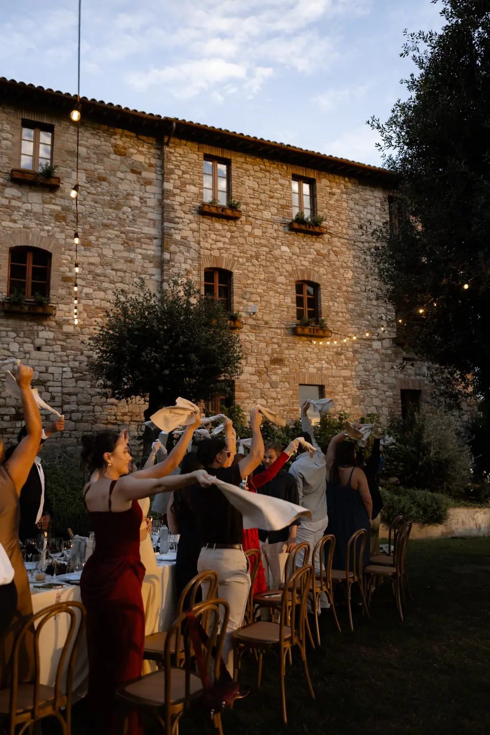 Guests waving napkins at the long table outside the stone monastery