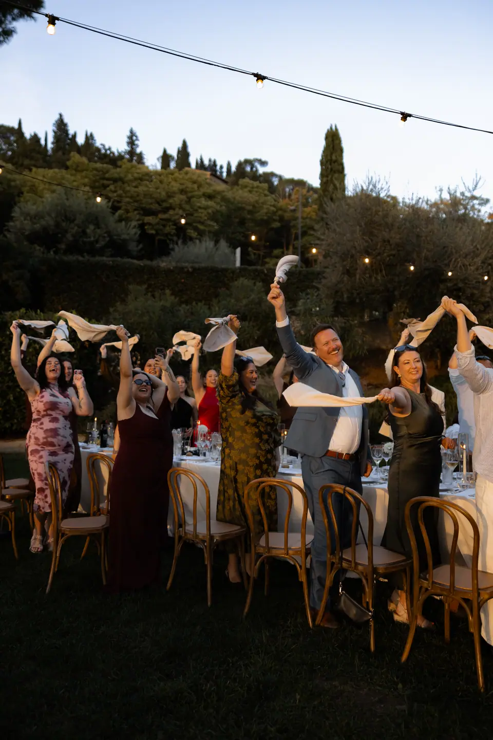 Guests on their feet twirling napkins as the couple arrive for dinner