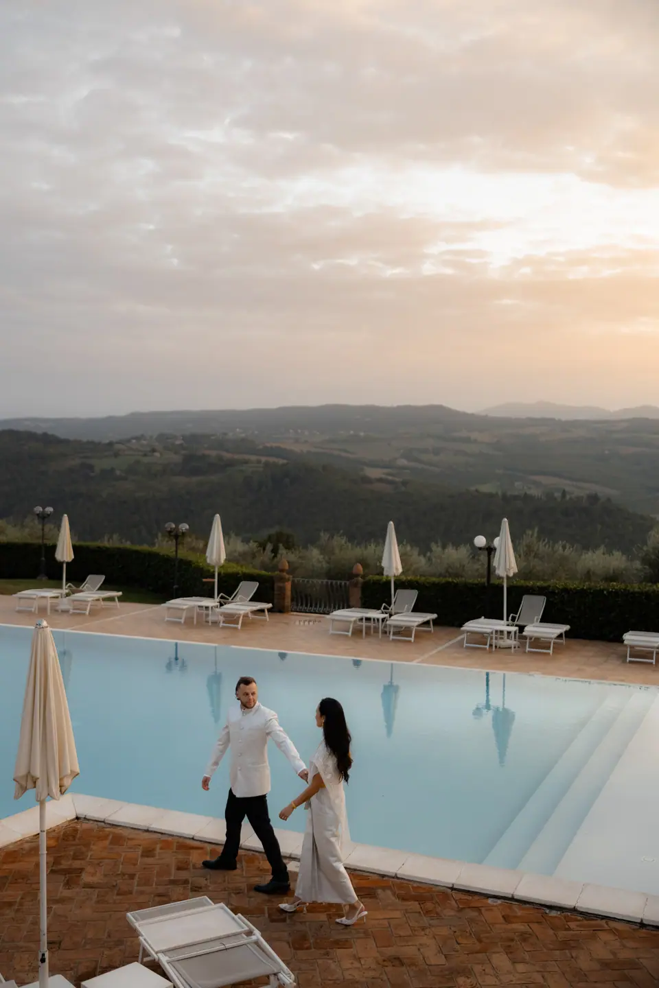 Sivitha and Rory walking by the pool at sunset, the hills beyond