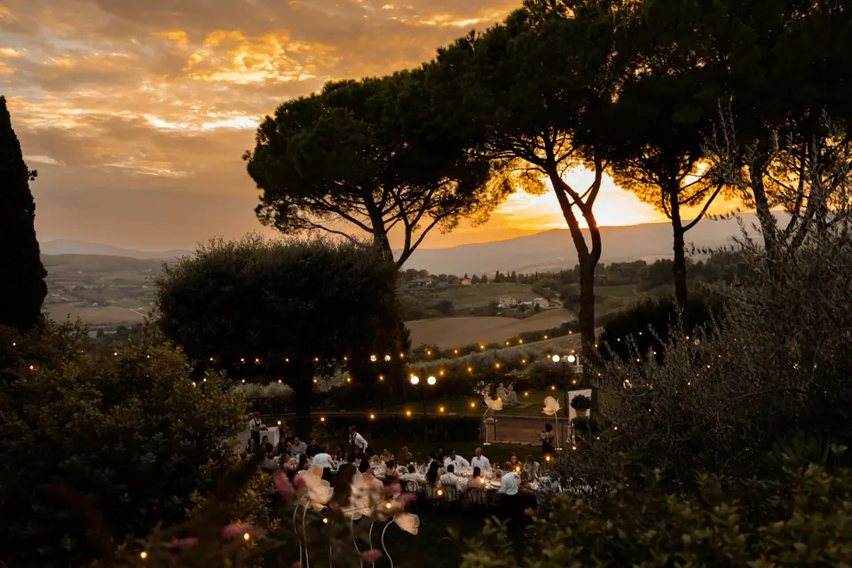 The sun setting behind umbrella pines above the candlelit dinner