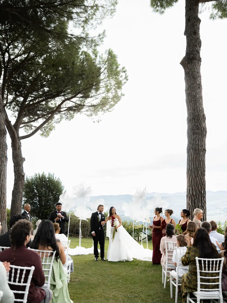 The garden ceremony between two umbrella pines, guests on either side of the aisle