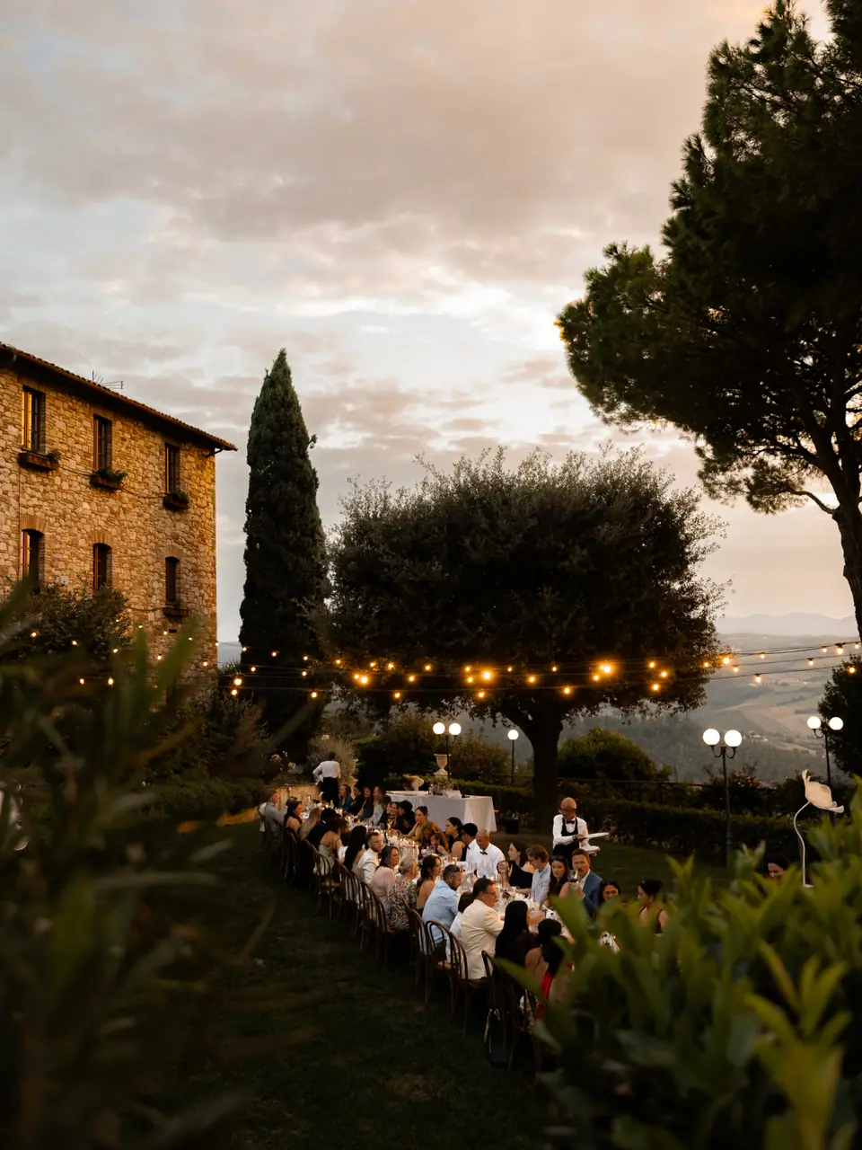 The long dinner glowing beside the stone monastery at sunset
