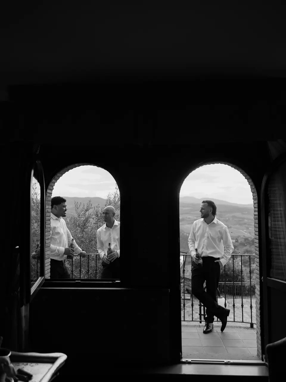 Black and white photograph of groomsmen in two arched doorways above the hills