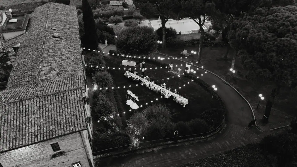 Black and white aerial view of the dinner tables and string lights beside the monastery at night