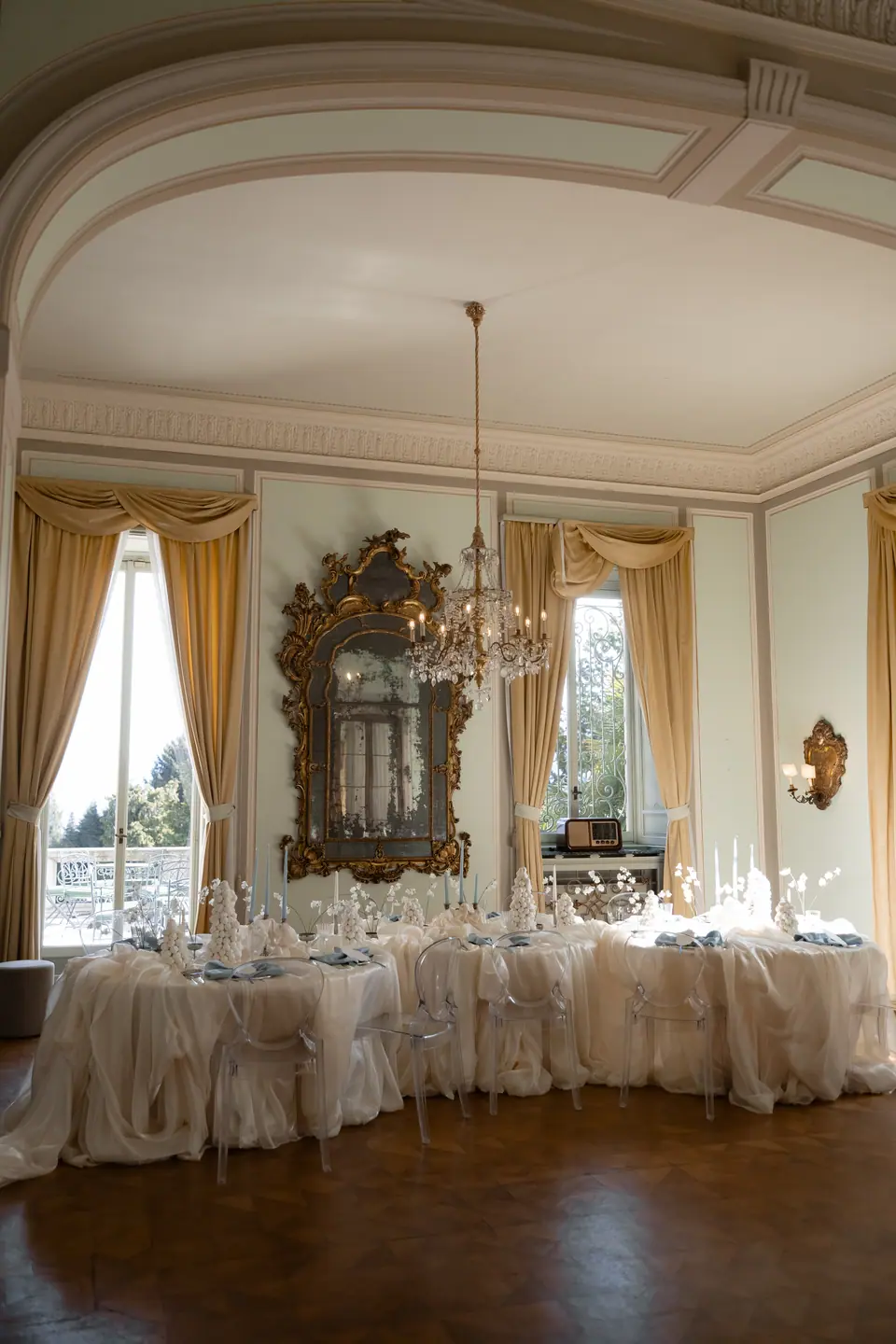 Villa dining room set with long tables, pale draping and gold curtains