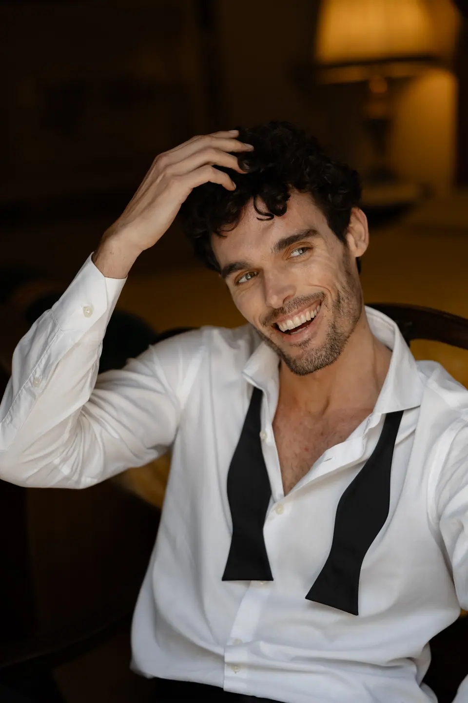 Antoine laughing and running a hand through his hair, his bow tie undone