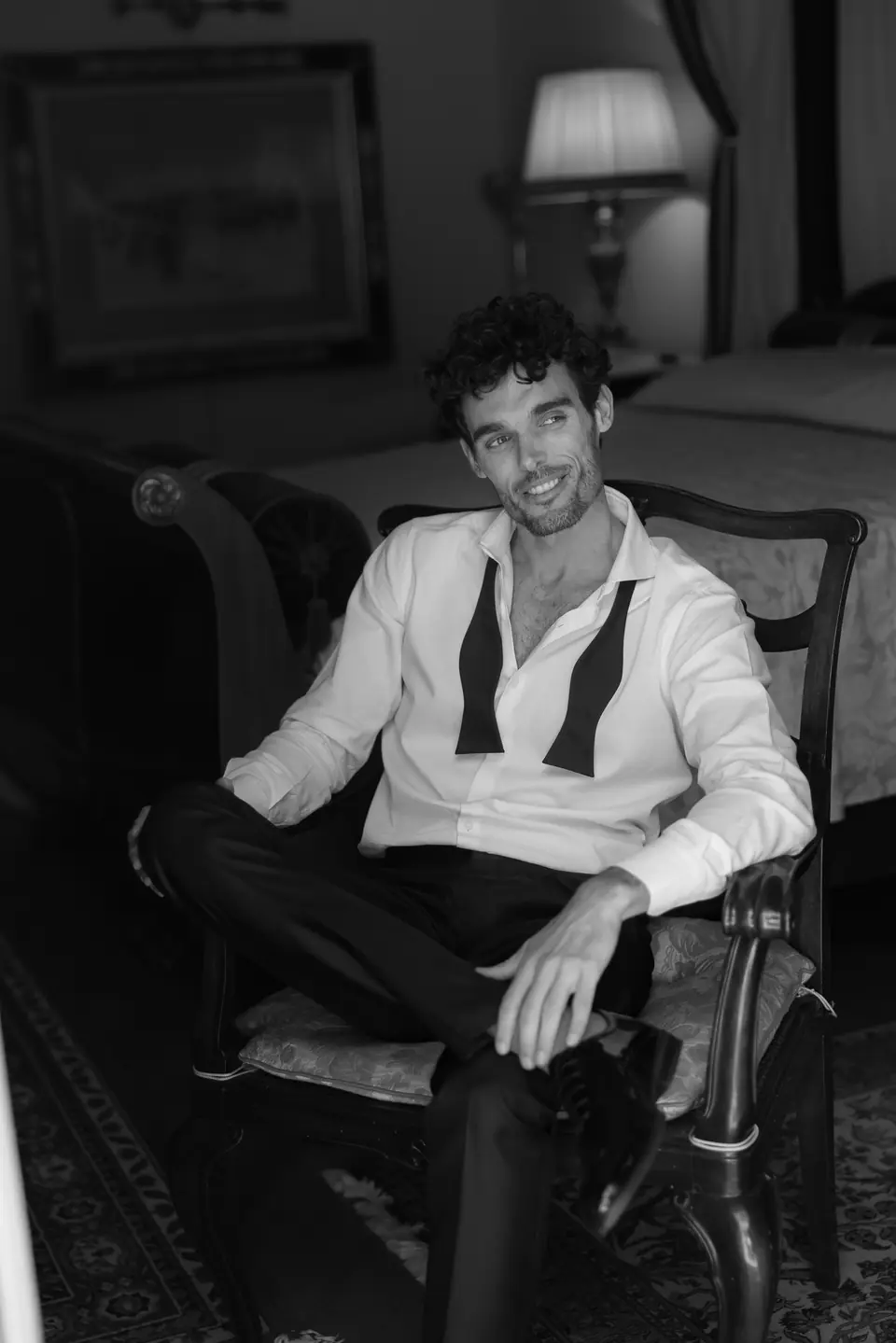 Antoine in black and white, seated in an armchair with his bow tie undone